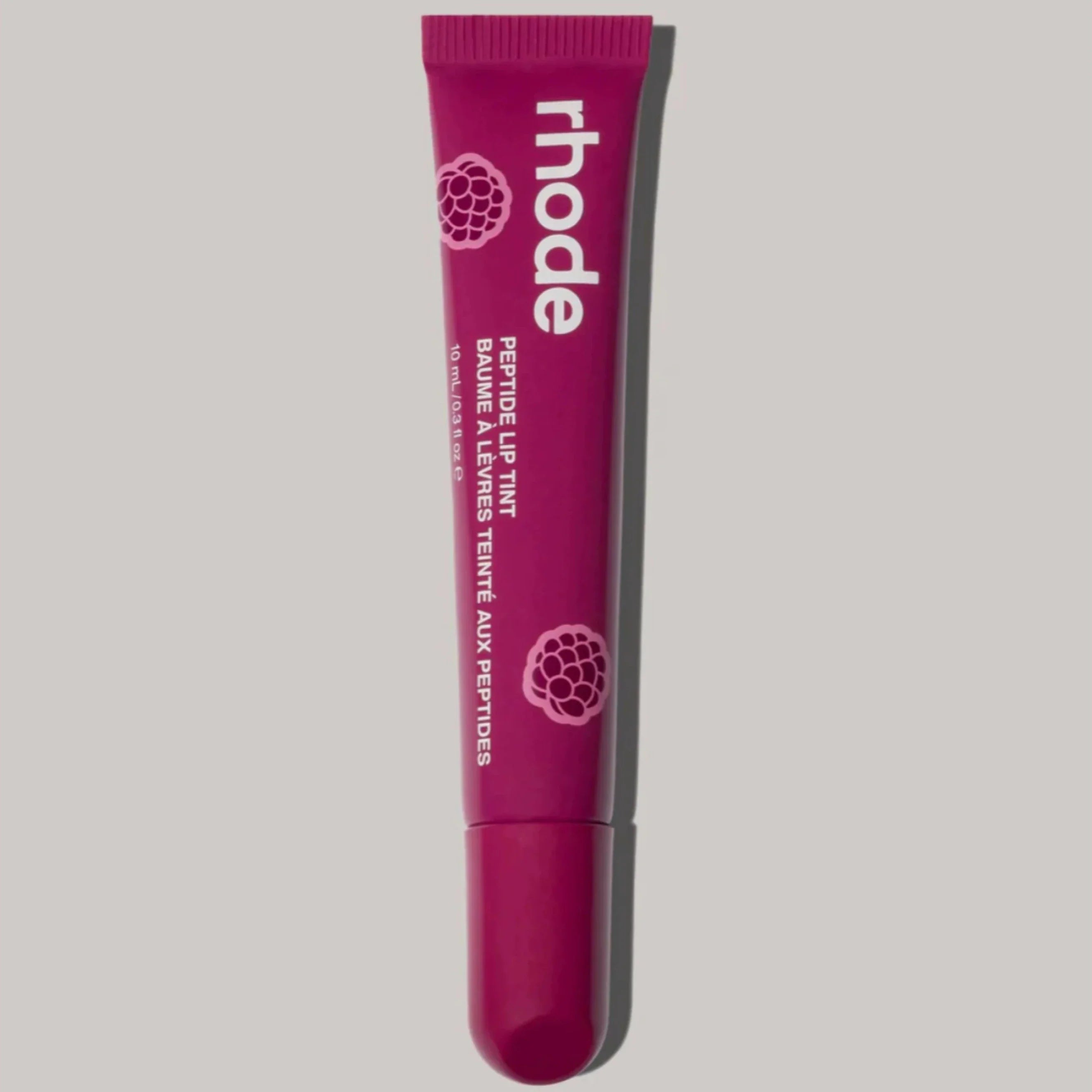 Pink lip balm tube with 'rhode' branding on a gray background