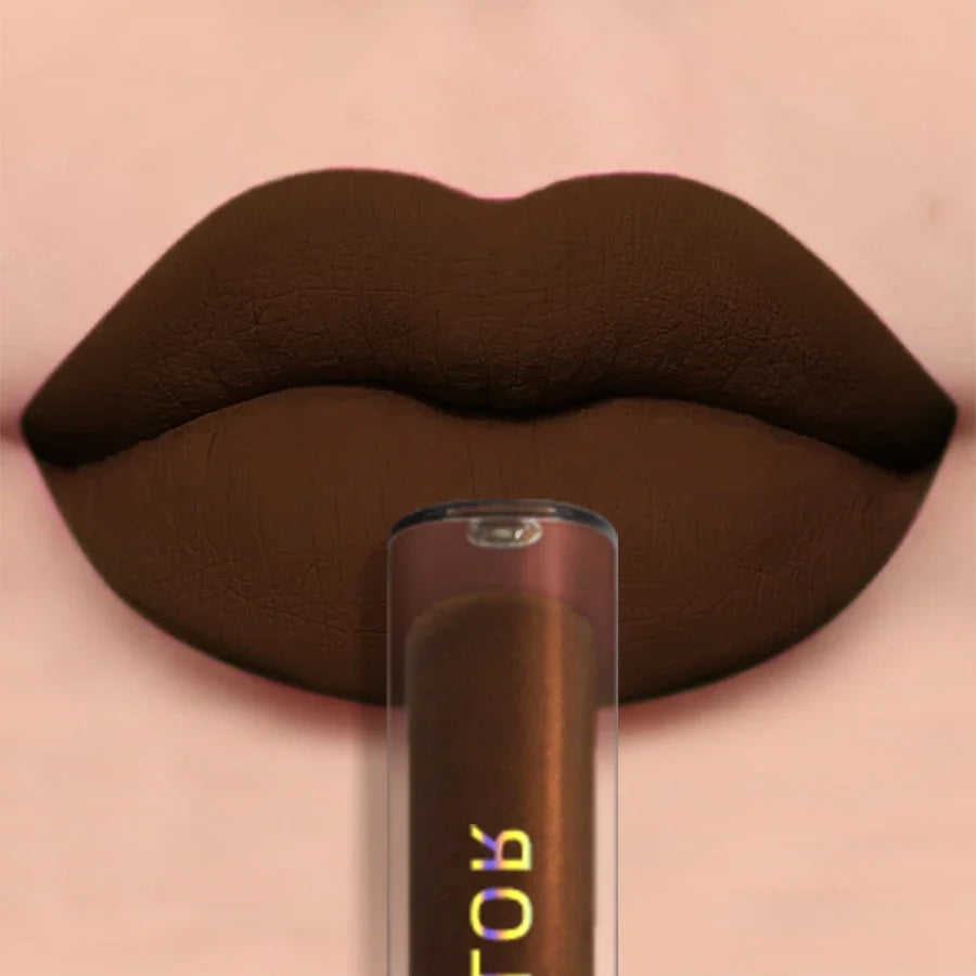 A close-up of lips wearing a matte dark brown lip color, with a matching lip product tube positioned in front against a soft pink background.