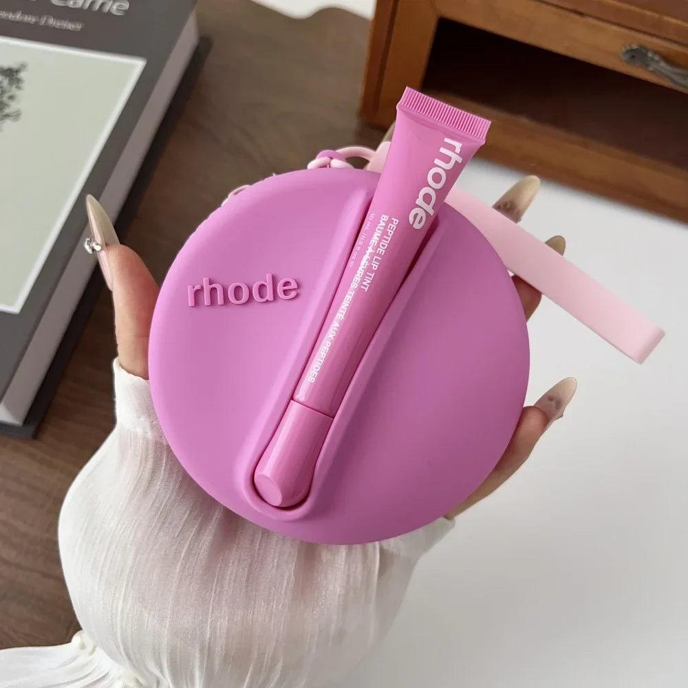 Pink 'rhode' case with a lip balm held by a hand on a light background