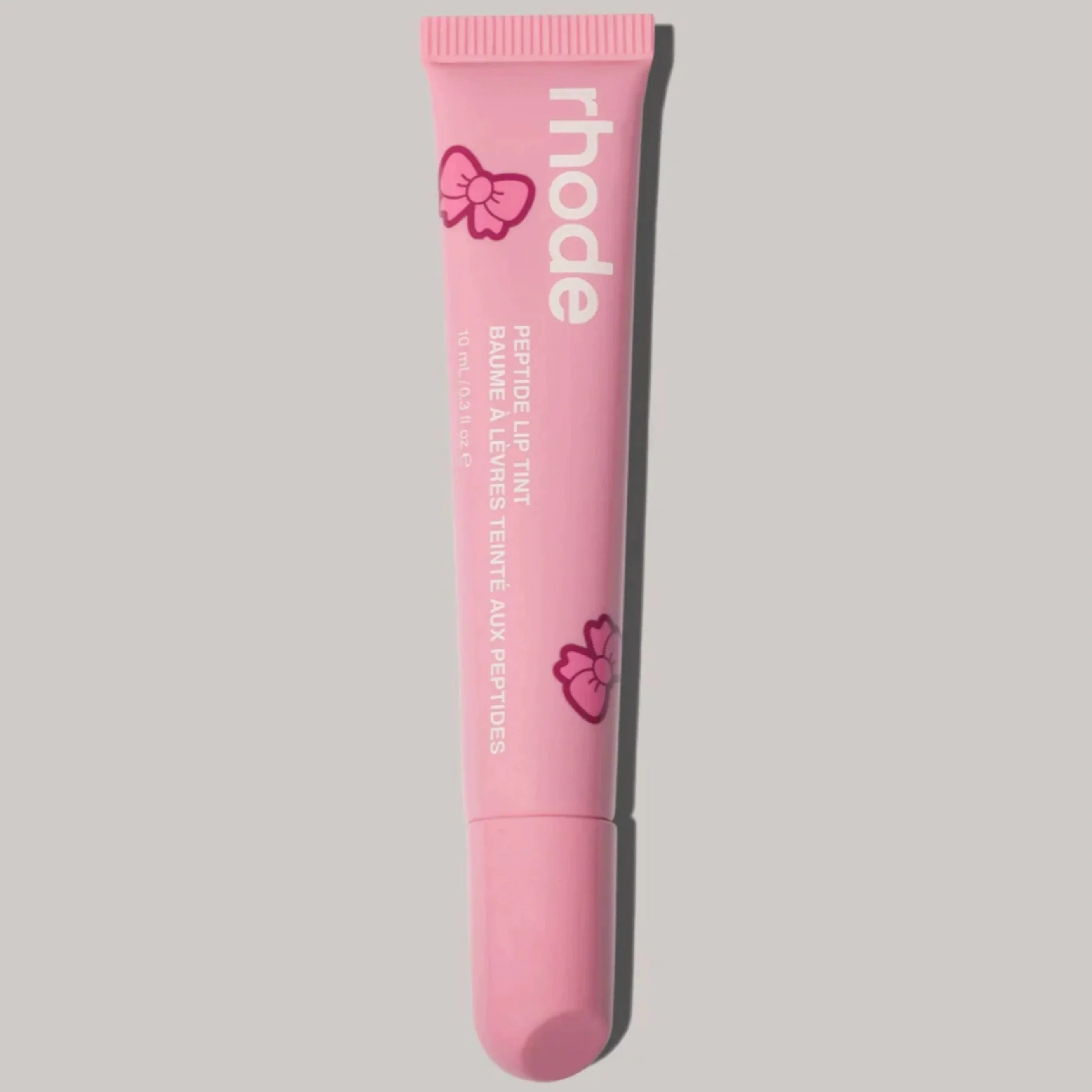 Pink lip balm tube with 'rhode' branding on a gray background