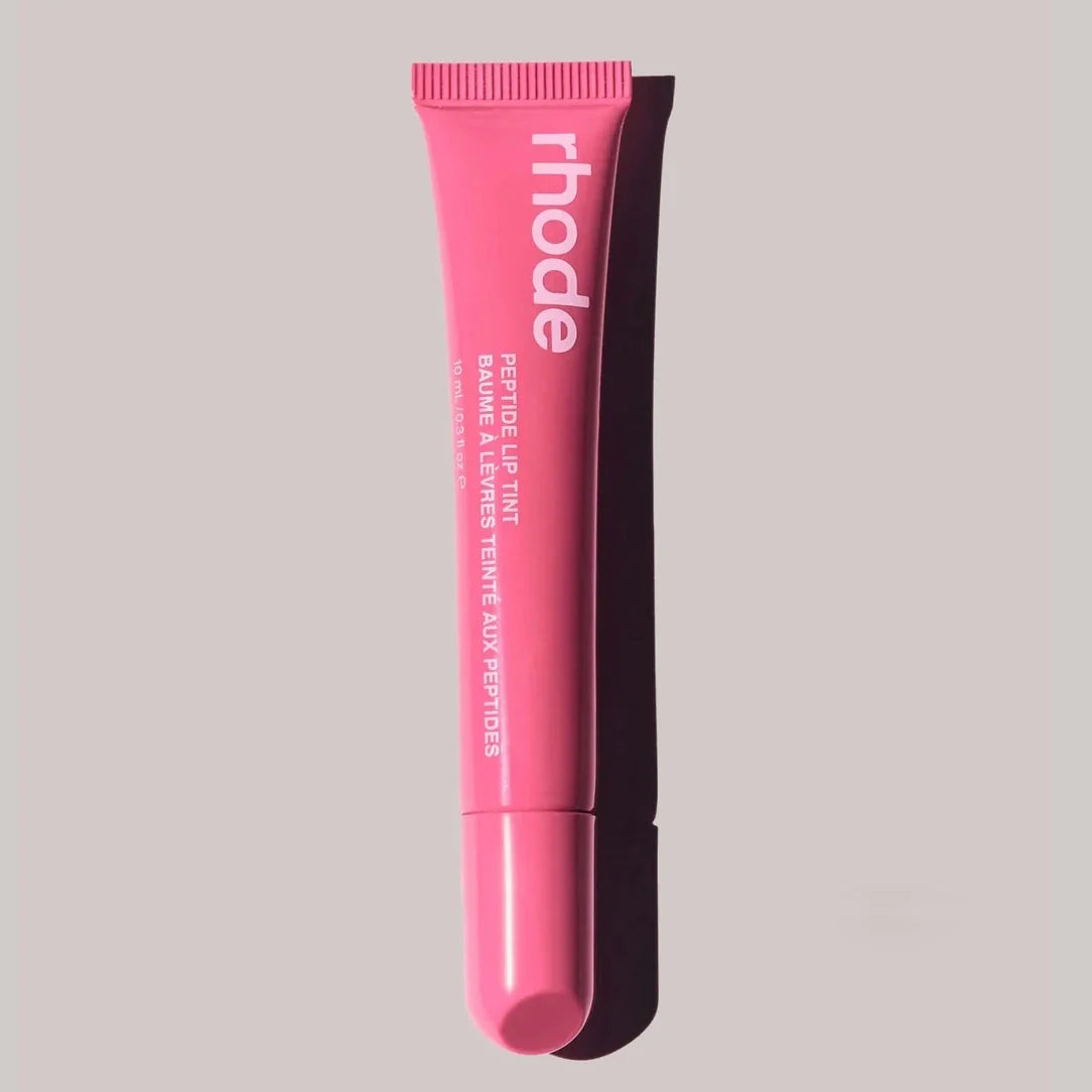 Pink lip balm tube with 'rhode' branding on a gray background