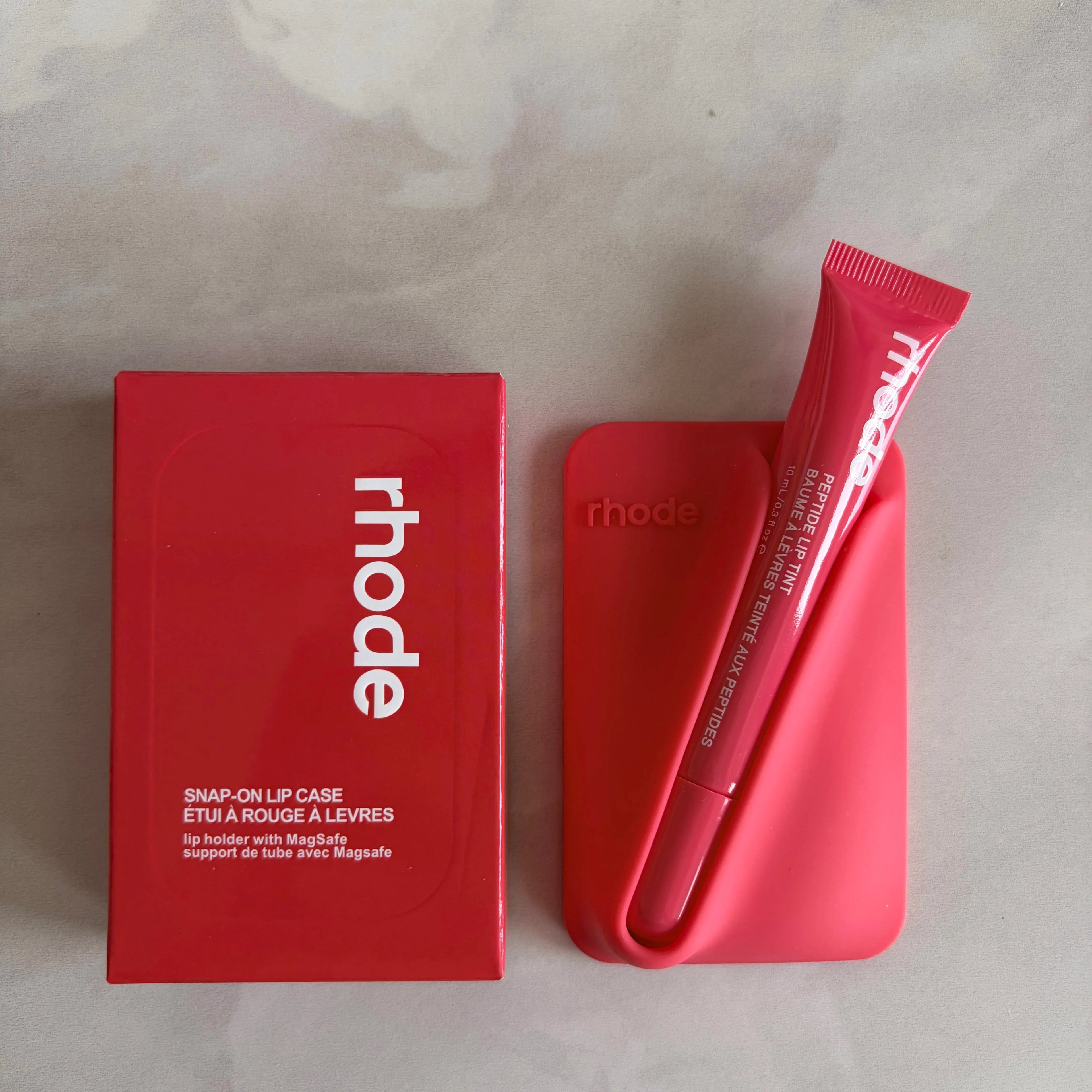 Red lip product with 'rhode' branding on a light gray background